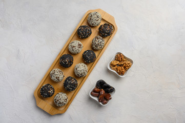 Homemade energy balls close up on wooden tray. Next to the vases with dates and walnuts