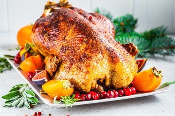 Christmas baked duck with herbs and fruits on gray plate, white background. © vaaseenaa