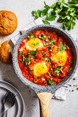 Traditional shakshuka in  pan. Fried eggs in tomato sauce with herbs, top view.