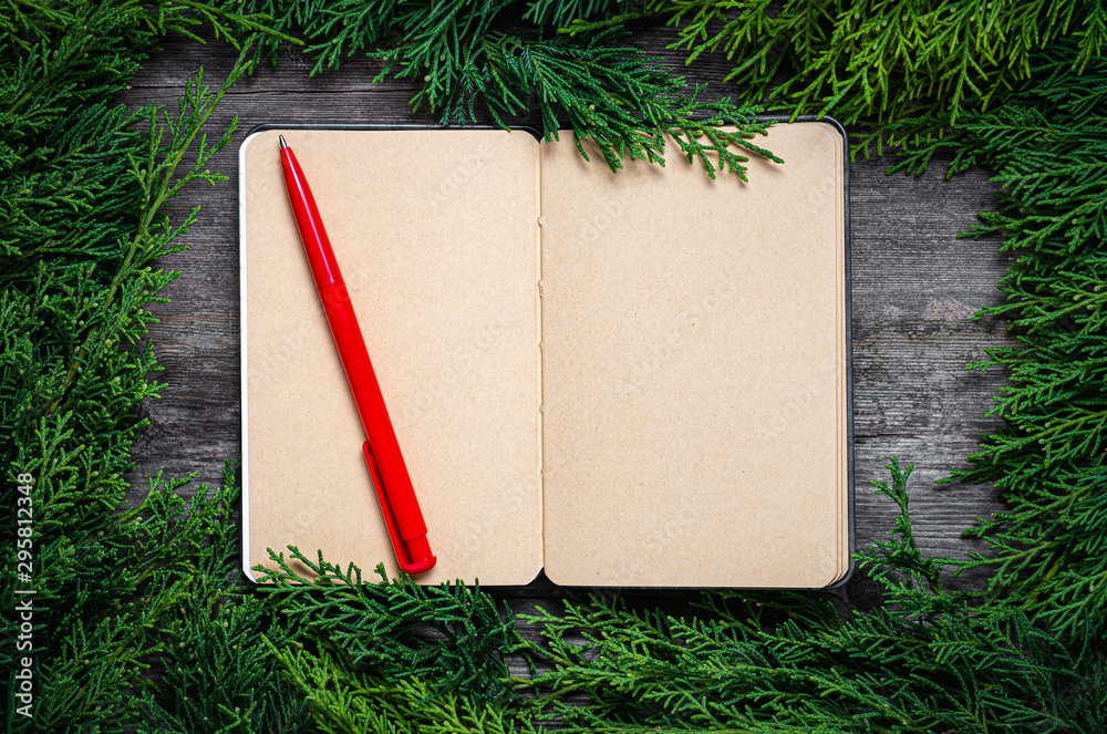 Wall mural christmas frame from fir branches on a background of an old gray board around an open notebook with 