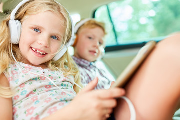 Children in the car listen to music with headphones