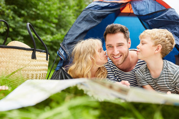 Children give father a kiss while camping