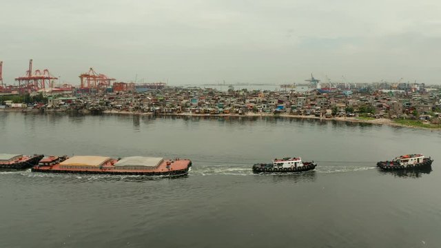 Aerial view of tugboats maneuvers other barges or vessel. Tugs and cargo ship on the river