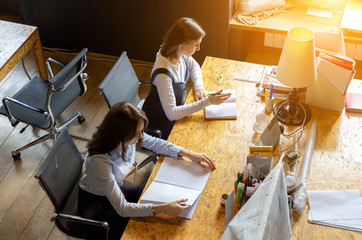 Business company of young and successful people. Young people sitting at their desks in the office. The concept of business and luck. A friendly team of two women and one man