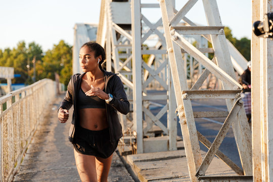 Photo of african american woman using earpods while running