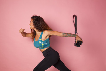 Atleta huyendo con su cámara fotográfica, corriendo con la cámara sobre fondo rosa