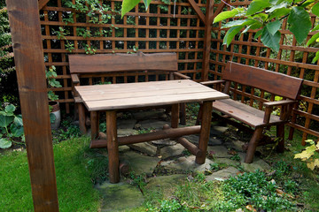 Wooden garden furniture standing in the gazebo with airy walls