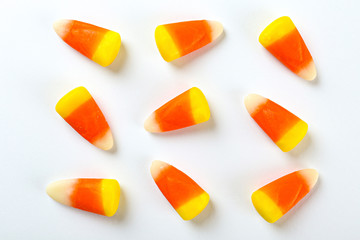 Bunch of candy corn sweets as sybol of Halloween hoiday on textured background with a lot of copy space for text. Flat lay composition for all hallows eve. Top view shot.