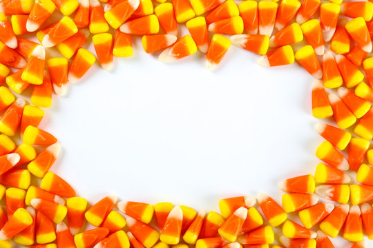 Bunch of candy corn sweets as sybol of Halloween hoiday on textured background with a lot of copy space for text. Flat lay composition for all hallows eve. Top view shot.