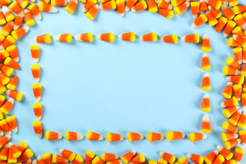 Bunch of candy corn sweets as sybol of Halloween hoiday on textured background with a lot of copy space for text. Flat lay composition for all hallows eve. Top view shot.