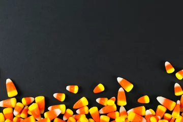 Fotobehang Bunch of candy corn sweets as sybol of Halloween hoiday on textured background with a lot of copy space for text. Flat lay composition for all hallows eve. Top view shot. © Evrymmnt