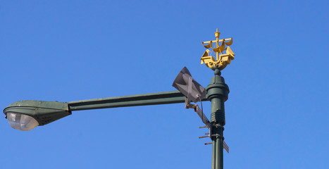 Fototapeta na wymiar The coat of arms of Lisbon, a golden caravel sailing ship and two crows mounted on a vintage street lamp post, commemorating the transfer of the relics of Saint Vincent of Saragossa to Lisbon.