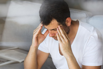 handsome businessman in white t-shirt thinking on the grey sofa in living room with free copy space for your text