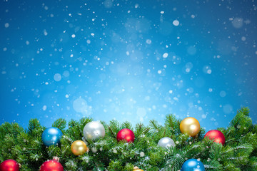 Fototapeta na wymiar christmas background with balls and fir branches, blue sky and snowflakes