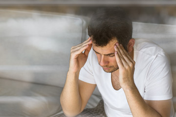 handsome businessman in white t-shirt thinking on the grey sofa in living room with free copy space for your text