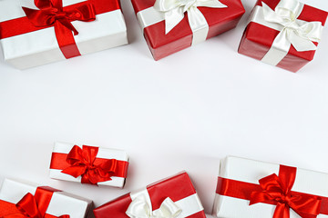 Bunch of christmas presents wrapped in red and white paper tied with shiny silk bow. Multiple new years gifts in different wrapping. Top view, close up, copy space, background, flat lay