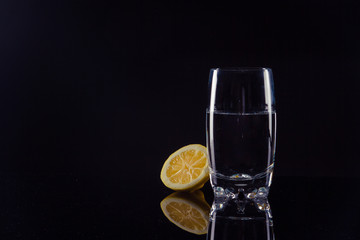 glass of water with a lemon on black background