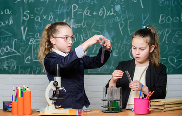Pupils cute girls use test tubes with liquids. Chemical experiment concept. Safety measures for...