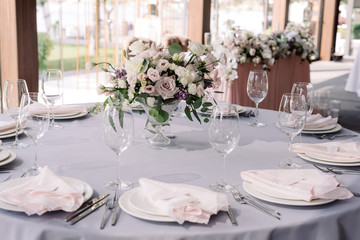 A luxurious bouquet of fresh flowers in a crystal vase on the holiday table and an elegant serving in the restaurant