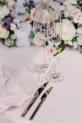 Beautiful glasses on the wedding table for champagne and wine against the background of flowers