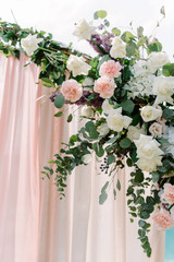 Wedding decorations with flowers. Pink cloves with gentle petals and flavor, white roses decorate wedding arch