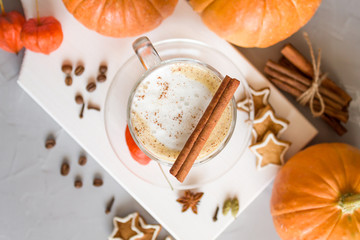 Pumpkin spice latte in a glass on a gray background. Pumpkins, coffee, cinnamon and cookies. Top view, copy space. Selective focus.