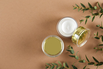Moisturizing care skincare face cream for healing complicated troubled skin type in an open jar with visible texture. Copy space, close up, background, flat lay, top view. Eucalyptus leaf decoration.