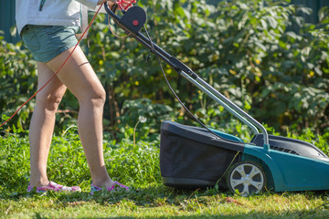 Woman cut the flower garden with an electric mower