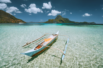 Palawan, Philippines. Traditional small fishing banca boat in front of Cadlao Island in crystal clear shallow water during low tide