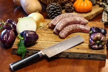 Selective focus still life of preparation of German bratwurst purple peppers and onions on wooden...