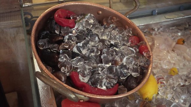 Chilled fresh mussels in a pot of ice and pepper on a restaurant counter.