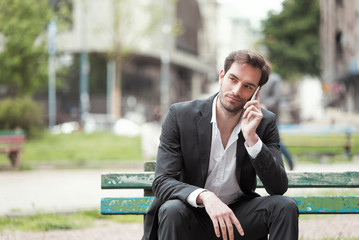 Handsome young businessman talking on his phone and looking bored