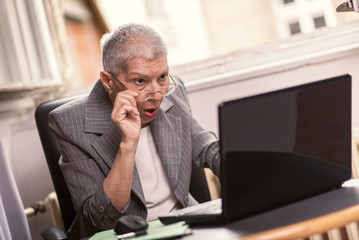 Senior old business lady in disbelief by an email on her laptop