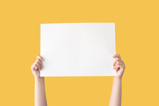 hand holding white blank paper isolated on yellow background with clipping path
