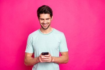 Photo of blogger guy holding telephone in hands checking subscribers toothy smiling wear casual...