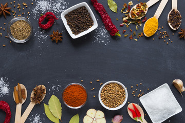 Colourful assorted herbs and spices and dry vegetable for cooking in wooden spoons and bowls on dark background with copy space. top view.