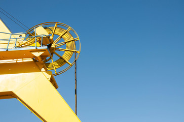 detail of yellow port crane on blue sky background
