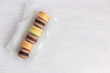 Set of French macarons on a white wooden table. Multicolored macarons. White background, pastel colors.