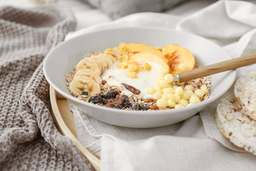 Bowl with tasty fruits, yogurt and granola on tray