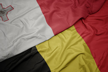 waving colorful flag of belgium and national flag of malta.