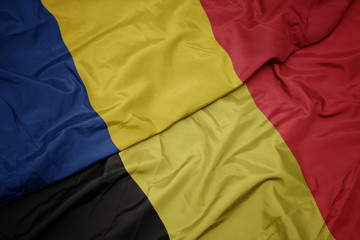 waving colorful flag of belgium and national flag of romania.