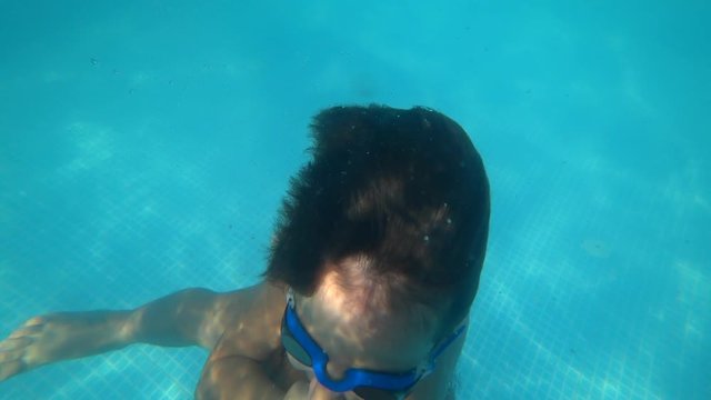 Kas, Turkey - 28th of September 2019: 4K Child training diving and swimming underwater in the countryside pool