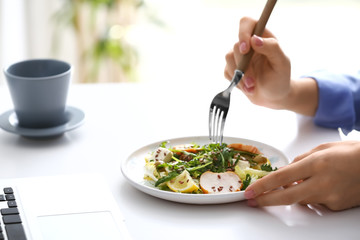 Woman eating tasty salad at home