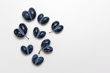 Ugly spoiled plum in the shape of a heart on a white background.