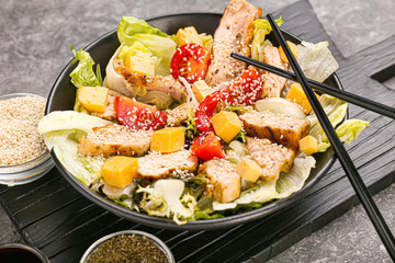 Plate with tasty salad and chopsticks on table