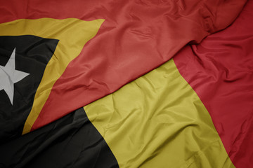 waving colorful flag of belgium and national flag of east timor.