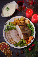 Roasted sliced ham on white plate, table with Christmas decorations. Dish for Christmas Eve. Winter season holidays food. Overhead, flat lay