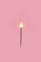 Sparklers light up on pastel pink background
