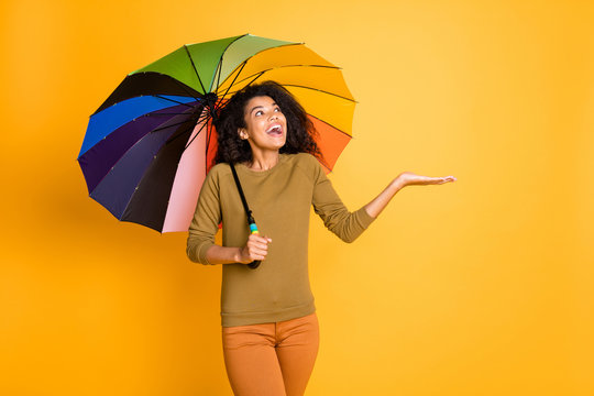 Photo of wavy cute nice charming pretty sweet girl excited about catching raindrops falling onto her hand holding umbrella hiding under isolated over vivid color background
