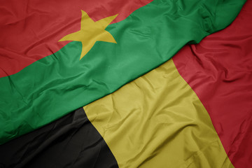 waving colorful flag of belgium and national flag of burkina faso.